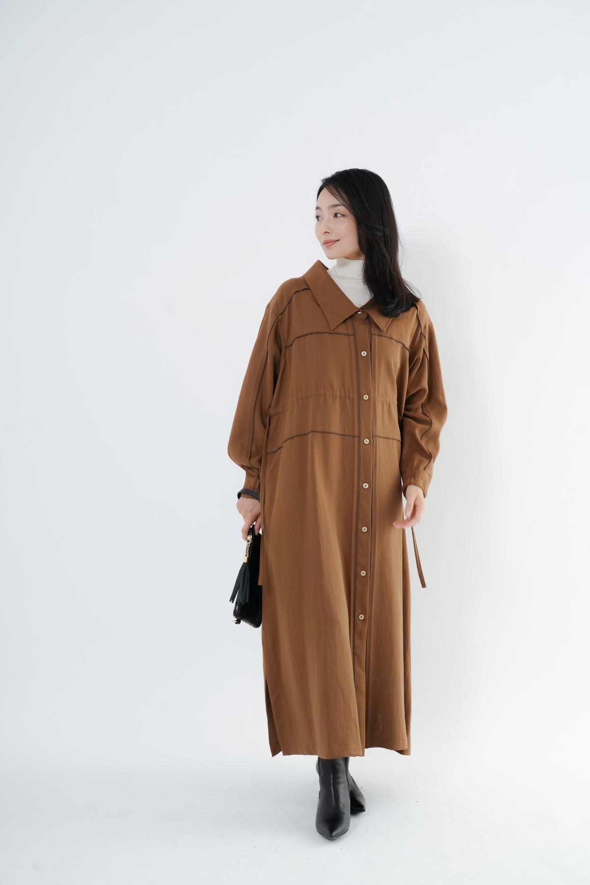 e-clothing-online storeのCLOCHEリブハイネックニットをインナーに合わせた、ブラウンのロングシャツワンピースを着用した女性