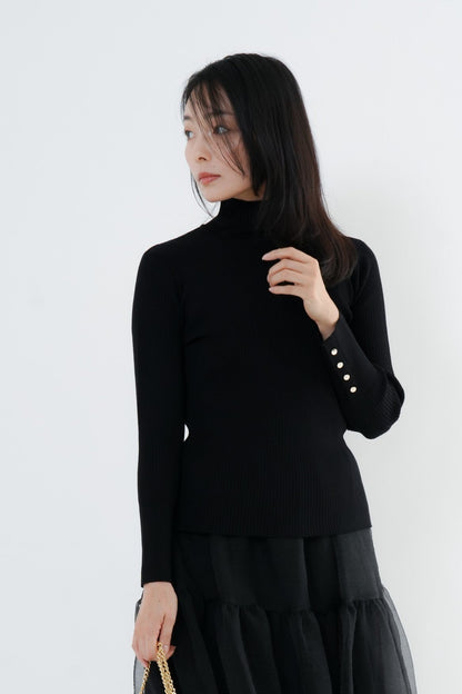 e-clothing-online storeのCLOCHEリブハイネックニット。袖口のゴールドボタンが特徴の黒いタートルネックニットを着用した女性モデル。