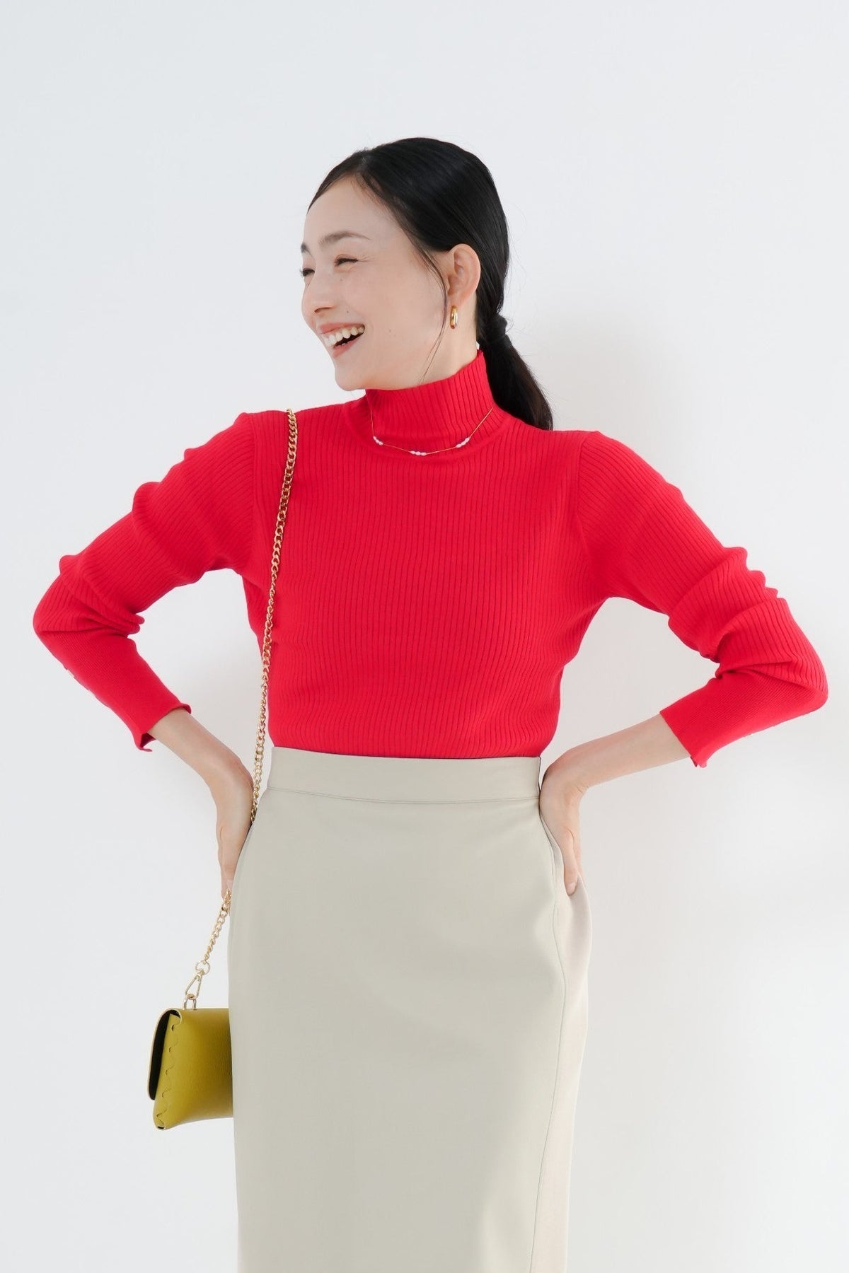 e-clothing-online storeのCLOCHEリブハイネックニットを着用した女性。鮮やかな赤のリブニットにベージュのロングスカートを合わせたきれいめなコーディネート。